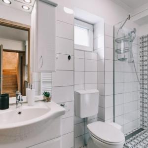 a white bathroom with a toilet and a sink at Békeapartmanház in Badacsonytomaj