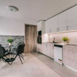 a kitchen with white cabinets and a table and chairs at Békeapartmanház in Badacsonytomaj +33 photos