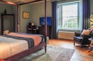 a bedroom with a bed and a chair and a window at Sancreed House B&B in Penzance