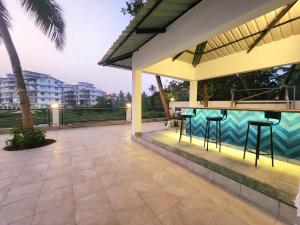 a patio with a bar and a swimming pool at La Vida Colva Beach Resort in Colva