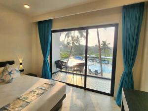 a bedroom with a large window with a view of a pool at La Vida Colva Beach Resort in Colva +94 photos