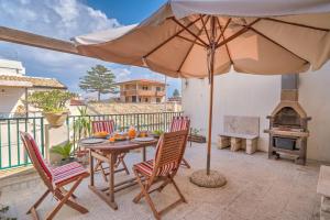 a patio with a table and chairs and an umbrella at Appartamenti Pomelia Punta Secca in Punta Secca