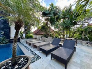 a patio with tables and chairs next to a pool at Mamo Hotel Uluwatu in Uluwatu