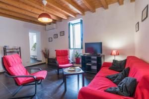 a living room with a red couch and chairs at Appartamenti Pomelia Punta Secca in Punta Secca