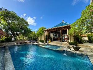 a swimming pool in front of a house at Mamo Hotel Uluwatu in Uluwatu