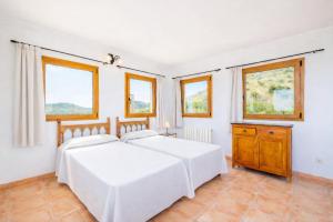a white bedroom with a bed and windows at Ca na Lluny in Artá