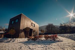 a wooden building in the snow with the sun behind it at La Villa Chalet and Spa in Polyana