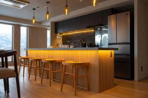a kitchen with a bar with wooden stools at The 1898 Niseko in Kutchan