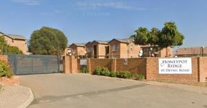 a fence in front of a brick building with a sign at Honeypot Ridge 29 in Honeydew