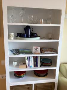 a white book shelf with plates and wine glasses at Sonne - Golf - 4Pers - Komfort - Apartments in Fuente-Álamo de Murcia