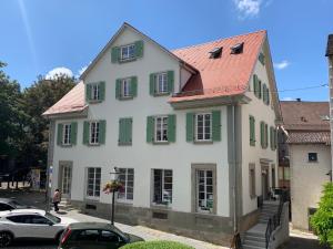 ein weißes Haus mit grünen Fensterläden und geparkten Autos in der Unterkunft Sani Suite in Backnang