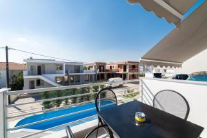 a balcony with a table and chairs and a swimming pool at Danai & Palm Stay Complex by Horizon Homes in Ofrínion