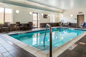 a pool in a hotel with chairs and tables at Sleep Inn & Suites Cumberland in Cumberland