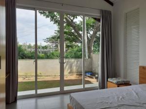 a bedroom with a large window with a view of a yard at Sathmani One in Nikawatawana
