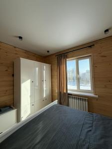 a bedroom with a bed and a window at Forest Club Burabay in Zhezdi