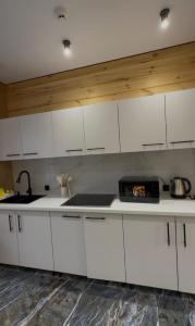 a kitchen with white cabinets and a sink at Forest Club Burabay in Zhezdi