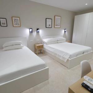 two white beds in a room with a desk and chairs at ResidenzaMarèa in Scalea