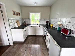 a kitchen with white cabinets and black counter tops at Finnsstaðir Holiday Home with Hot tub in Egilsstaðir