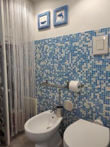 a blue tiled bathroom with a toilet and a sink at La Tana in Formia +29 photos