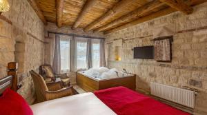 a bedroom with a bed and a tub in a room at Zula Cave House in Ürgüp