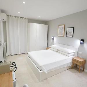 a white bedroom with a large bed and a table at ResidenzaMarèa in Scalea