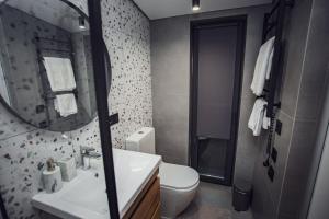 a bathroom with a toilet and a sink and a mirror at La Villa Chalet and Spa in Polyana +22 photos