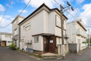 a white house with a door on a street at Soresta INN Shinozaki in Tokyo