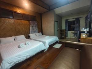 a bedroom with two beds with towels on them at Pai Tewdoi ปาย ทิวดอย รีสอร์ท in Pai +12 photos