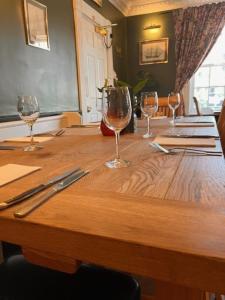 a wooden table with four wine glasses on it at The Ilchester Arms Hotel, Ilchester Somerset in Ilchester