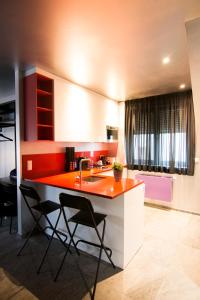 a kitchen with a counter with a sink and chairs at Hôtel JJ32 Luxembourg Centre Gare in Luxembourg