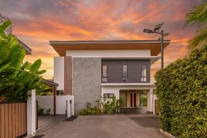a house with a sunset in the background at Luxe & Privacy Orchard Villas Pasak 4BR in Laguna Phuket