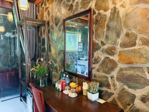 a table with a mirror and a stone wall at Trang An Mountain River Ecolodge in Ninh Binh