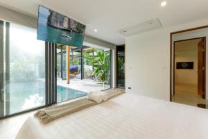 a bedroom with a large bed and a large window at Luxe & Privacy Orchard Villas Pasak 4BR in Laguna Phuket +26 photos