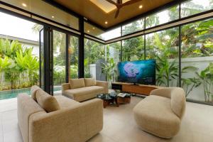 a living room with two chairs and a flat screen tv at Luxe & Privacy Orchard Villas Pasak 4BR in Laguna Phuket