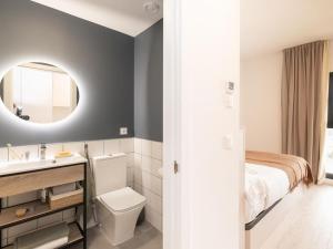 a bathroom with a toilet and a sink and a bed at Canvas Sabadell Llac in Sabadell