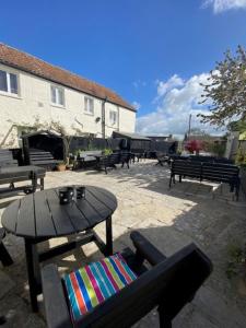 a patio with benches and a table and a table and chairs at The Ilchester Arms Hotel, Ilchester Somerset in Ilchester +15 photos