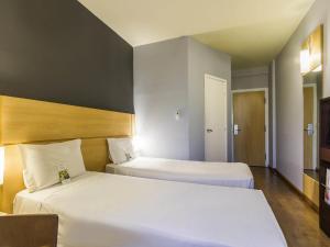 two beds in a hotel room with two beds at ibis Barretos in Barretos