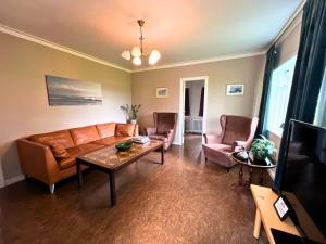 a living room with a couch and chairs and a table at Finnsstaðir Holiday Home with Hot tub in Egilsstaðir +23 photos