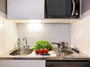 a kitchen counter with a sink and vegetables on a cutting board at Aparthotel Adagio Access Paris Maisons-Alfort in Maisons-Alfort