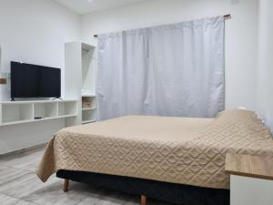 a bedroom with a bed and a flat screen tv at Mirasoles Suites in Monte Grande