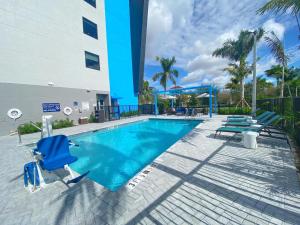 a swimming pool with blue chairs and a building at Tru By Hilton Miramar in Miramar