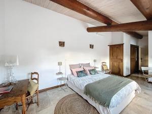 a bedroom with a large bed and a wooden desk at Clos des Cassis - Maison d'Hôtes in Villeneuve