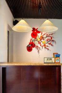 two lights above a counter with red flowers on the wall at Hoi An Canal House Riverside By Haviland in Hoi An