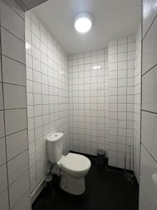 a bathroom with a toilet and a white tiled wall at 36 flat 1 - Room 2 in Swansea
