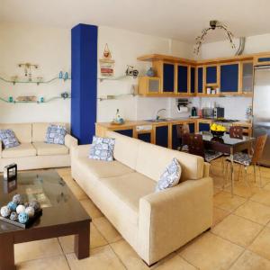 a living room with two couches and a kitchen at Derveni Seaside Apartments - Deluxe Sea View Penthouse Jacuzzi-BBQ & Groundfloor Garden View Apartment in Derveni