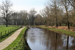 a river in a park with a path and trees at Bed&Breakfast de Hooimoat in Losser