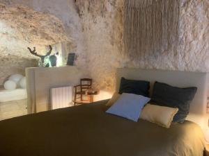 a bedroom with a bed in a stone wall at Les Troglos de la Tufolière in Rochecorbon