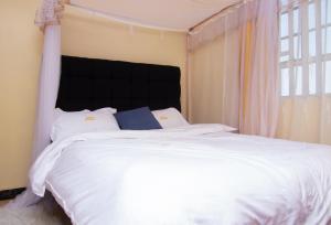 a bedroom with a large white bed with a large window at Zariah Homes 1BR Ksm in Kisumu