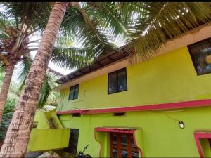 a yellow house with palm trees in front of it at Sharvati Backwater Homestay in Haldipur