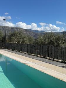a swimming pool with a fence and mountains in the background at Pauz Hotel in Himare